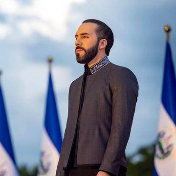 A bearded man in a gray jacket stands in front of El Salvador and other flags, with the post quoting Nayib Bukele on buying market dips. The image aligns with the message, presenting the President of El Salvador—known for his country's Bitcoin investments—as the speaker behind the quote about strategic market timing.