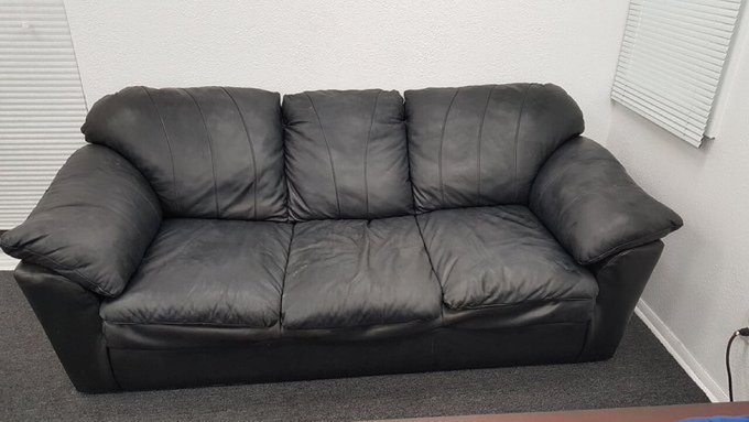 The image shows a black leather couch placed against a white wall with a window nearby. The couch appears to be old or worn out, possibly indicating that it has been used for an extended period of time. The photo also contains text related to Bitcoin, Solana, and other cryptocurrency-related terms, suggesting that the owner might be interested in investing in digital assets or is involved in some form of online business related to cryptocurrencies.