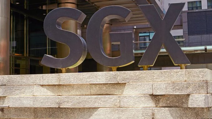 Large metallic letters spelling 'SGX' sit atop a stone ledge outside a modern building.