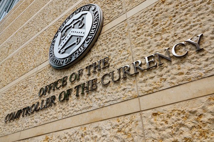 A low-angle photograph of a textured stone building exterior displaying a metallic seal that reads 'OFFICE OF THE CONTROLLER OF THE CURRENCY' alongside large raised metal lettering spelling out 'OFFICE OF THE CONTROLLER OF THE CURRENCY'.