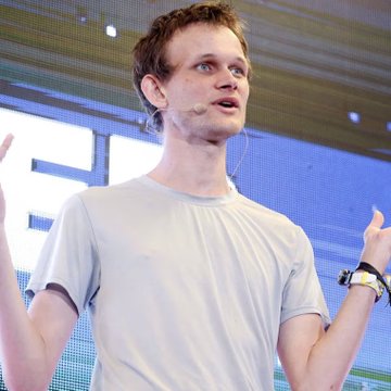 A young man with light brown hair, wearing a gray t-shirt and a headset microphone, speaks expressively with raised hands during what appears to be a tech presentation, matching the post about Vitalik Buterin unveiling Ethereum's "Lean Ethereum" transformation roadmap.
