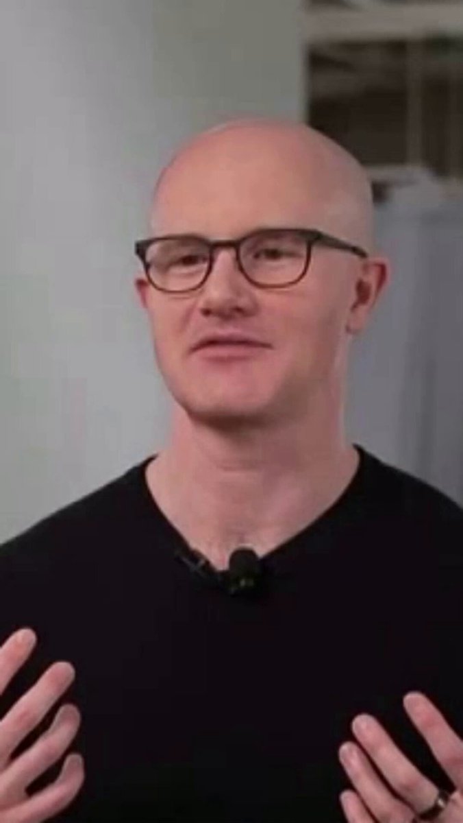 The image features a bald man wearing glasses and a black shirt with his hands up in front of him, as if he's giving a speech or presentation. The caption below the image reads "the vision was already there. back in 2025, brian armstrong explaining ai-powered financial advisors and the everything exchange." This suggests that the image is related to an event or discussion involving Brian Armstrong, who has been advocating for AI-powered financial advice services.