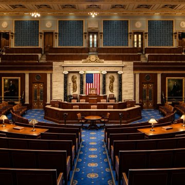 An ornate, empty legislative chamber, likely a U.S. House of Representatives hall, with an American flag displayed centrally at the front dais. The image's depiction of a quiet, governmental setting contrasts with the post's casual, trading-floor slang, creating an ironic juxtaposition between formal politics and informal market banter.