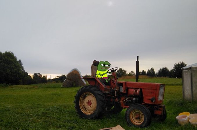 A Pepe the Frog character is digitally superimposed sitting on a red tractor in a grassy field under a cloudy sky.