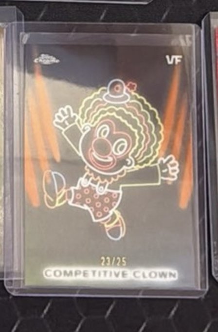 A holographic foil trading card labeled 'COMPETITIVE CLOWN' (23/25) featuring a cartoon clown running with a raised fist.