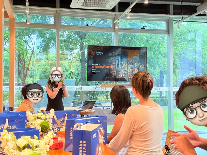 A speaker addresses an attentive audience during an indoor presentation event, with a screen displaying what appears to be social media content in the background, capturing the collaborative atmosphere of the closed-door Web3 HR and recruiter meeting.