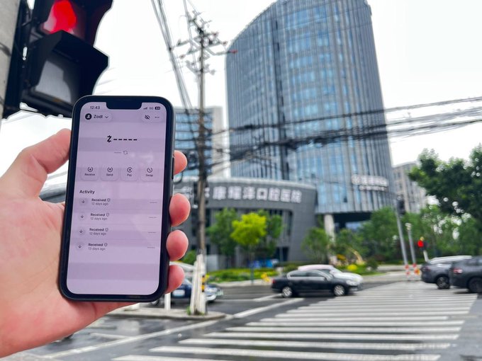 The image shows a person holding up their phone, which displays an app called "ZEC + a Sentinel powered dVPN @norselabs = freedom". The person's hand is visible above the phone screen as they look at the app details or possibly share information with someone else in the scene.