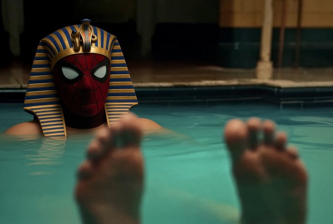 A creative image showing Spider-Man wearing an Egyptian pharaoh headdress while partially submerged in a swimming pool, with two hands visible in the foreground.
