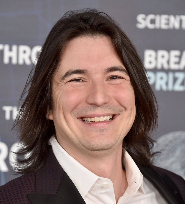A man with long dark hair smiles at what appears to be the Breakthrough Prize ceremony, with "SCIENCE," "BREAKTHROUGH," and "PRIZE" visible on the backdrop behind him. The image does not appear to be directly related to the post about Robinhood Chain's DEX trading volume and memecoin activity.

Note: I can describe the image but cannot identify the specific person shown.