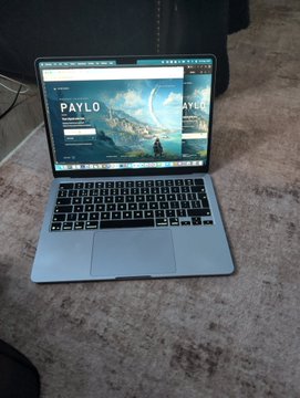 An open laptop sits on a desk displaying a website with the text 'PAYLO' on its screen.