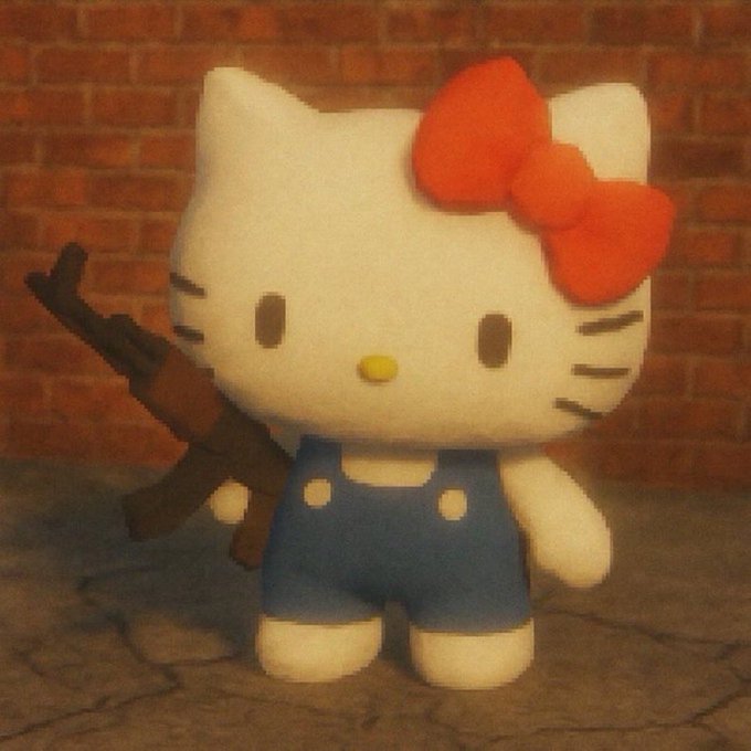 A small handmade clay figurine of Hello Kitty wearing blue overalls and a red bow, holding what appears to be an assault rifle, photographed against a brick wall background.