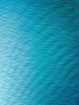 A close-up aerial or surface view of rippling teal-blue water showing gentle waves and texture