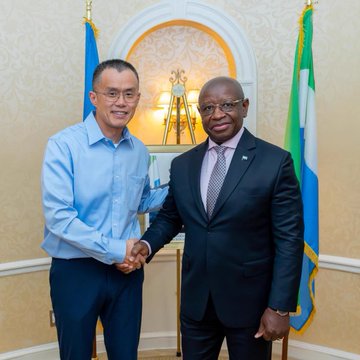 Binance founder Changpeng Zhao (CZ) shakes hands with Sierra Leone's President Julius Maada Bio during an official meeting to discuss Bitcoin and crypto adoption, symbolizing growing government-level engagement with digital assets across Africa. The formal setting, with national flags displayed, underscores the seriousness of crypto-policy discussions on the continent.