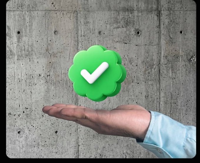 A hand holding up a green cloud-shaped icon with a white checkmark, set against a textured gray concrete wall.