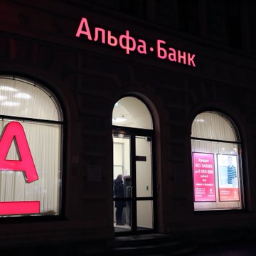The image shows the exterior of an Alfa-Bank branch with its name illuminated in Russian. This relates to the news that Alfa-Bank, Russia's largest private bank, plans to launch a digital depository for crypto services.