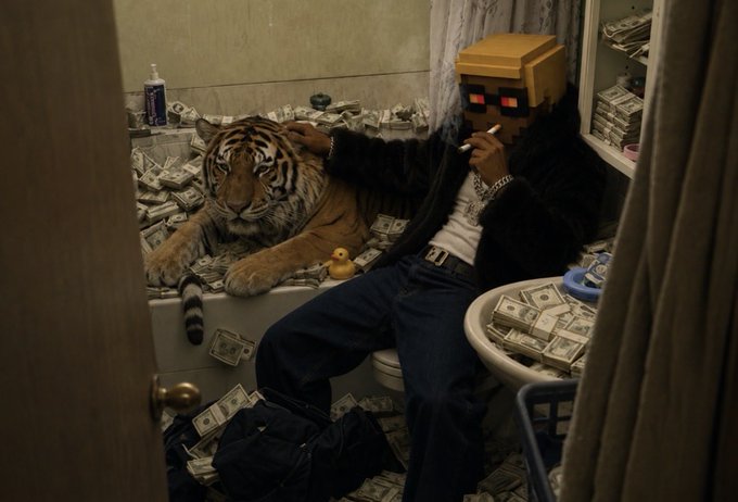 A Minecraft-style character with blonde hair and red sunglasses smokes a cigarette while sitting on a toilet in a bathroom filled with US dollar bills, with a live tiger beside them and a rubber duck on the tub.