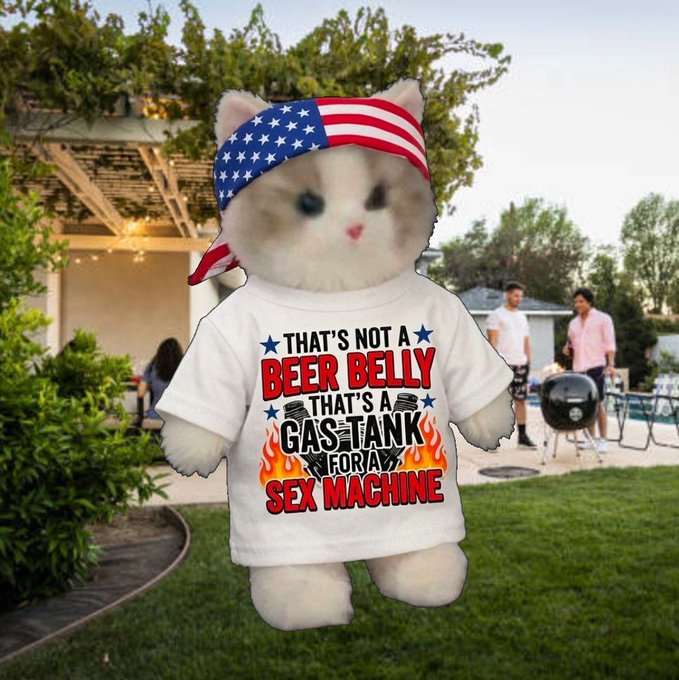 A plush kitten wearing an American flag bandana and a white t-shirt reading "THAT'S NOT A BEER BELLY THAT'S A GAS TANK FOR A SEX MACHINE" stands on a lawn at a backyard barbecue, fitting the "Miumerica" theme with its patriotic flair and humorous Independence Day–style humor.