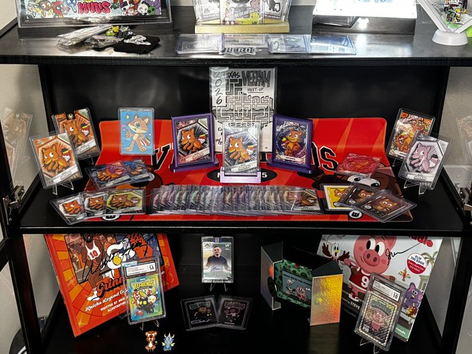A display shelf showcases Pokémon trading cards, TCG boxes, and merchandise, including boxes of "151" and various graded cards in protective cases.