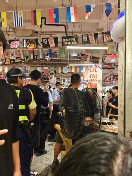 In this image, police officers are present in a market setting adorned with flags and banners, possibly responding to an incident related to the post's mention of calling the cops.