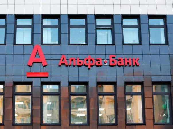 The image shows the facade of an Alfa Bank building, with the bank's logo (a red "A") and name displayed in Cyrillic reading "Альфа·Банк" in red lettering on a dark paneled exterior above several windows. This visually represents Russia's largest private bank mentioned in the post about its plans to launch XRP and crypto depository services as part of the country's evolving digital asset regulatory framework.