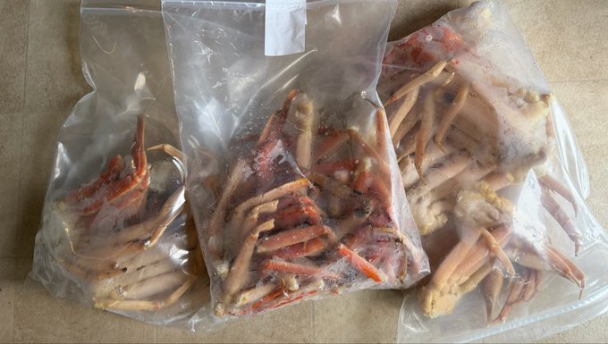 Three clear plastic vacuum-sealed bags containing crab legs and claws, appearing to be stored as frozen seafood.