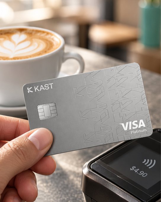 A hand holds a silver 'KAST VISA Platinum' card over a contactless payment terminal showing $4.90, with a latte featuring leaf latte art in the background.