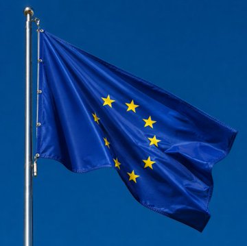 The image shows the European Union flag—blue with a circle of twelve yellow stars—waving against a clear blue sky. It visually ties into the post by symbolizing the EU's Markets in Crypto-Assets (MiCA) regulatory framework and Crypto.com's passporting across 30 EU countries.