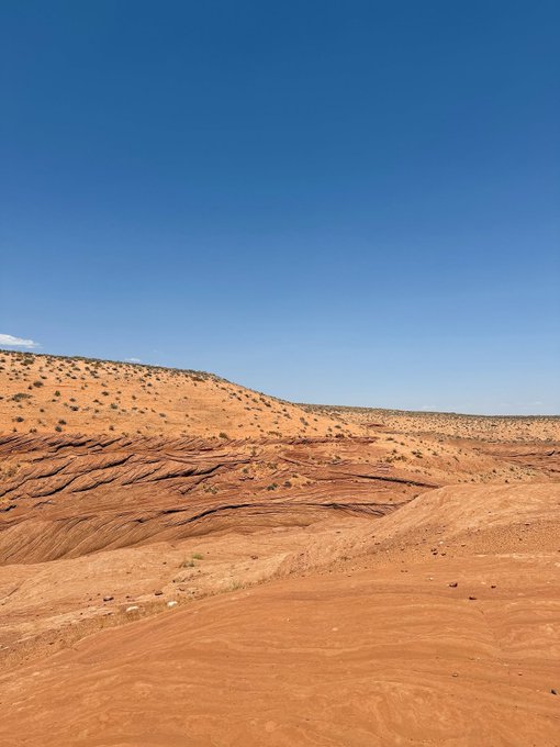 A landscape photo of red rock desert terrain under a clear blue sky.