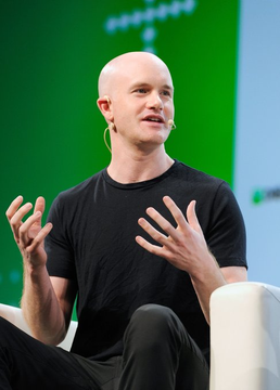 Coinbase CEO Brian Armstrong gestures while speaking on stage at a conference, with the post announcing Coinbase's newly secured MiFID license enabling the company to offer equities and derivatives trading to UK users.