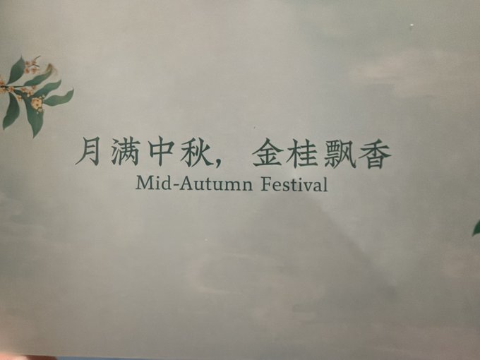 A promotional card or package featuring Chinese text "月满中秋，金桂飘香" (translates to "Full moon of Mid-Autumn, fragrance of golden osmanthus") with the English subtitle "Mid-Autumn Festival," decorated with illustrated osmanthus flowers on a soft cloud-like background. This appears to be a thoughtful Mid-Autumn Festival gift from @web3houzi, reflecting the appreciation expressed in the post for receiving two rounds of meaningful gifts.