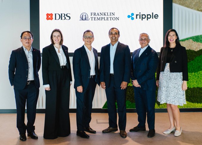 Six people in business attire pose for a photo in front of a backdrop displaying the DBS, Franklin Templeton, and Ripple logos.