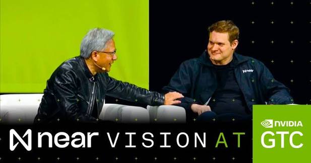 Two men conversing on stage at the NEAR VISION AT NVIDIA GTC event, with one wearing a leather jacket and the other in a NEAR hoodie, shaking hands while seated on a couch.