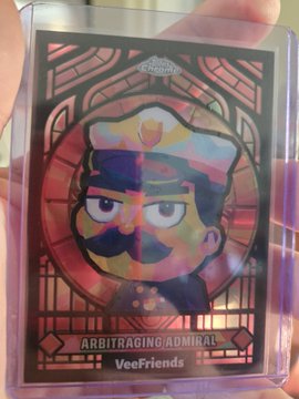 A holographic Topps Chrome trading card featuring a character labeled "ARBITRAGING ADMIRAL" from VeeFriends, showing a stylized figure with a captain's hat and mustache in vibrant rainbow colors.