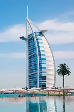 A futuristic sail-shaped waterfront hotel or tower rises behind a pool and palm trees under a clear blue sky. It illustrates Google’s new policy of allowing licensed Bitcoin, cryptocurrency exchanges, and wallet apps to advertise in the United Arab Emirates; no text or logos are visible in the image.