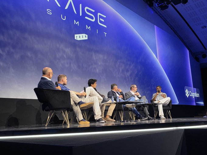 A panel of six speakers sits on stage at the Raise Summit (TRSN) in Paris, with a large backdrop displaying the event's logo against a blue sky and the Cognizant sponsor logo visible to the right—capturing the high-quality speaker lineup referenced in the post about the event's impressive industry developments.