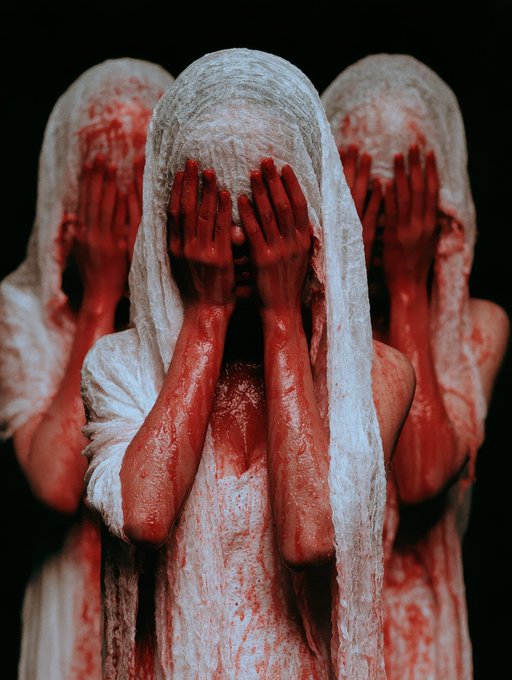 Three figures draped in white, blood-stained fabric cover their faces with red-stained hands against a black background.