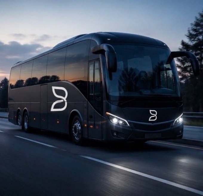 A sleek black luxury tour bus with a stylized 'B' logo driving on a highway at dusk.