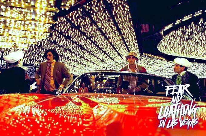 The image depicts four men sitting inside a car with one of them wearing a cowboy hat and sunglasses, suggesting an outdoor setting like a desert or beach during sunset. They appear to be having a conversation while enjoying their time together. The image also includes text elements such as "Fear & Lightning in Las Vegas" and "100% daily for a start". This post appears to be promoting an action movie that takes place on a desert island, where the main characters fear lightning, seeking shelter and trying to survive.