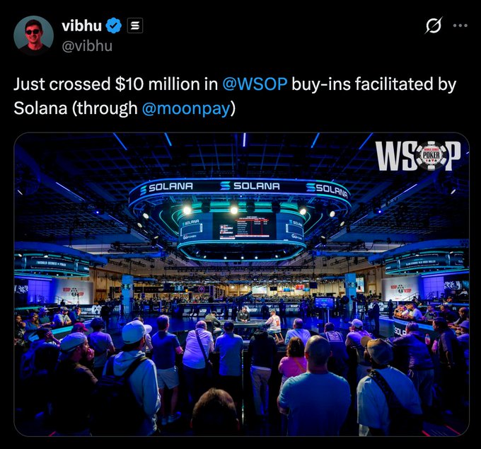 The image shows a large crowd of people gathered at an event featuring an indoor stadium with numerous booths and banners, including one that reads "Just crossed $10 million in #WSOP buy-ins facilititated by Solana (through @moonpay). Focus on what is in the image and how it relates to the post.". The event seems to be a trade show or conference where companies are showcasing their products and services.