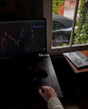 A dimly lit room where a person sits at a desk with a computer displaying financial trading charts; the text "The risk" is overlaid on the center of the image.