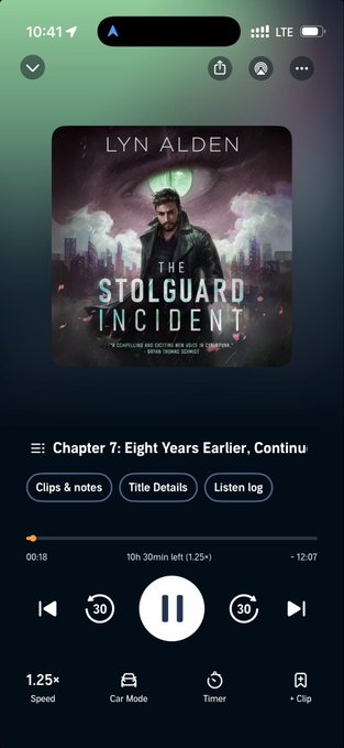 A smartphone screen displays an audiobook player streaming "The Stølguard Incident" by Lyn Alden, currently paused at Chapter 7 with 10 hours 30 minutes remaining. The playback interface shows the book cover featuring a bearded man against a purple mountainous backdrop, alongside standard controls including 1.25x speed and chapter navigation buttons, complementing the post about enjoying fantasy audiobooks during a long road trip.