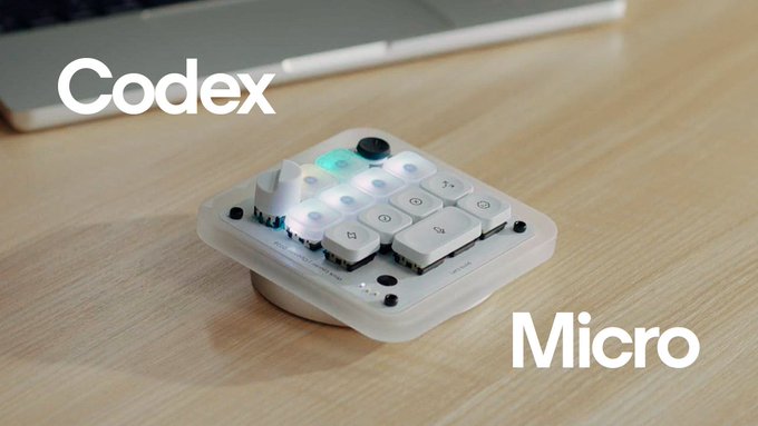 A small white macropad labeled "Codex Micro" sits on a wooden desk near a laptop, illustrating the continuation of the Codex brand with a new compact product.