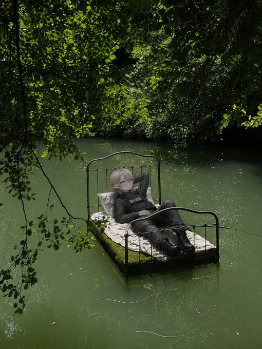 The image features a person lying down on a bed that has been placed in a body of water, possibly a lake or pond. The person appears to be enjoying their time in this unique setting. The surrounding area includes trees and bushes, adding to the serene atmosphere. The caption provided seems to be related to an advertisement for Bitcoin Cash, which is likely meant to capture attention and generate interest in the product being advertised.