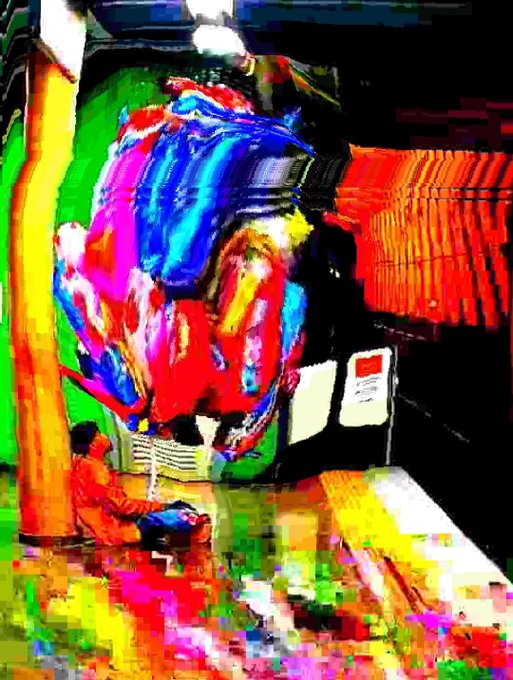 A highly stylized, colorful artwork with a digital painting effect shows a person sitting before a large, abstract display of red, blue, and yellow.