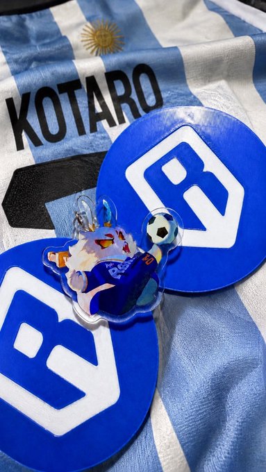 An Argentina-style soccer jersey with the name 'KOTARO' and number 7 is displayed alongside matching coasters and a small character keychain holding a soccer ball.