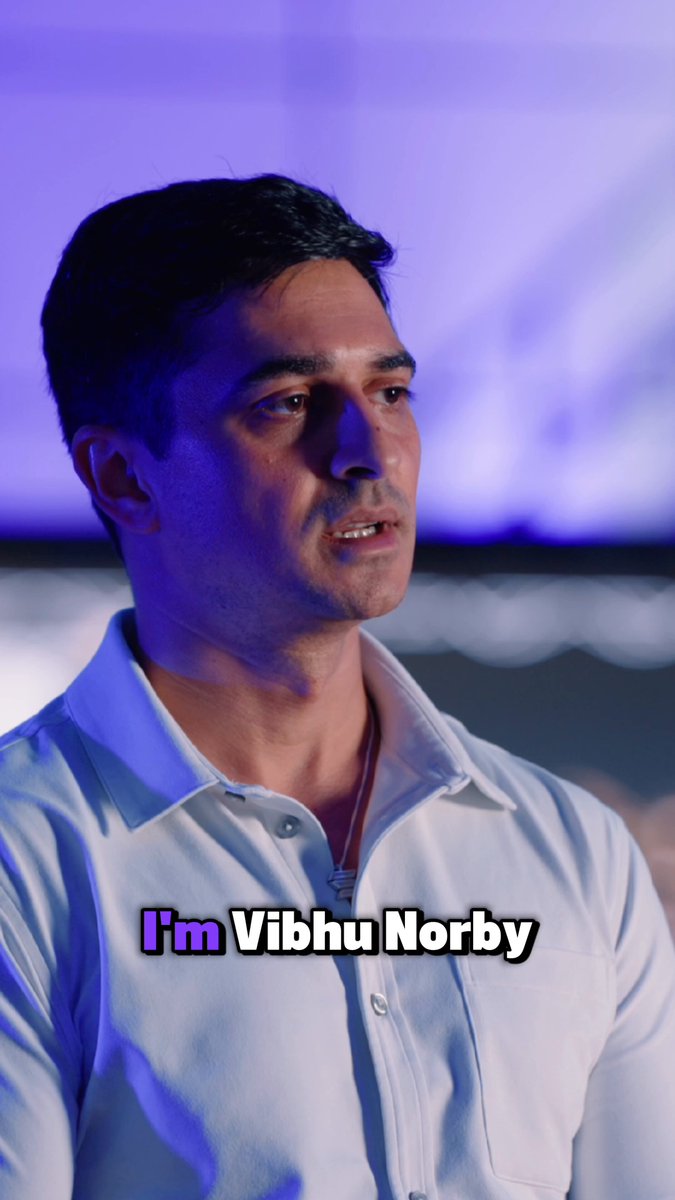 The image features a man wearing a white shirt, looking off into the distance with a serious expression. The background of the photo has a blue hue that contrasts with the man's attire. There are no texts or other objects present in the image.