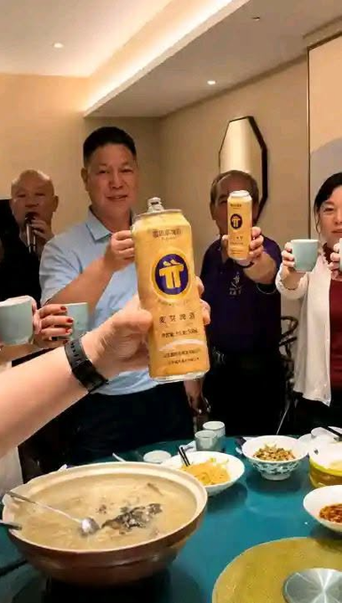 A group of people at a dinner table raise drinks for a toast, with bottles of 'TT' brand liquor prominently held up.