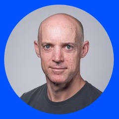 A bald man with blue eyes and a dark t-shirt is shown in a circular portrait against a bright blue background. The image appears to accompany a post about a key Dogecoin figure joining Coinbase, suggesting the man pictured is likely that individual (possibly linked to the $DRB token mentioned in the post).