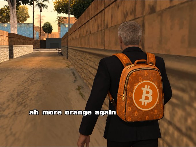 A video game screenshot showing a man in a suit walking down an alley wearing an orange Bitcoin-patterned backpack, with the caption 'ah more orange again'.