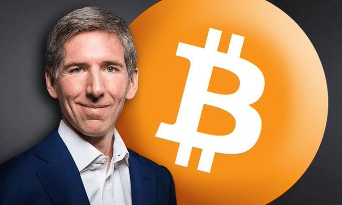 The image features a man wearing a suit, standing next to an orange circle with the letter "B" inside of it. The man appears to be smiling for the camera while posing against this backdrop. The caption above the photo reads, "Bitwise CIO: Only those who have reached the top should consider investing in Bitwise." This suggests that the image is related to a post about investing in Bitcoin or other digital assets.